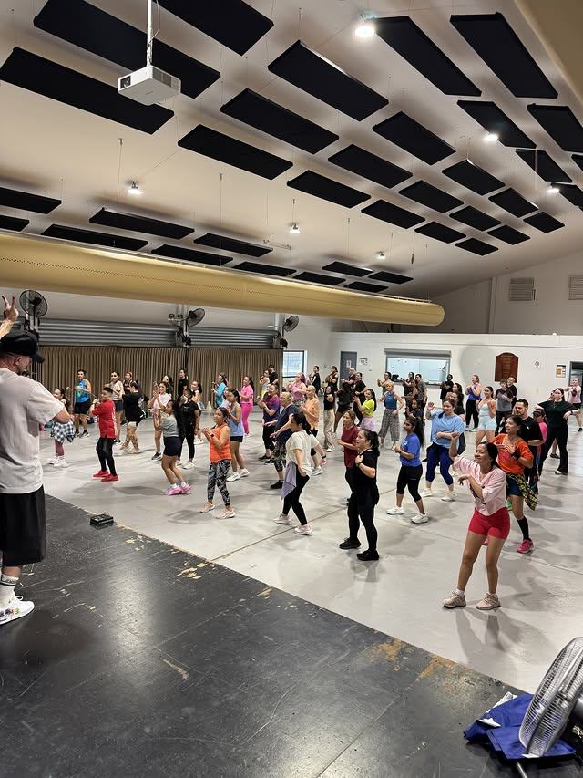 A busy class dancing in rows, everyone facing the front of the hall.