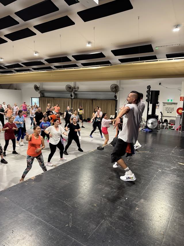 An instructor at the front of the room demonstrating a step to the class.