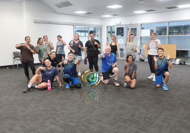 A group photo in the carpeted community room after a weeknight class.