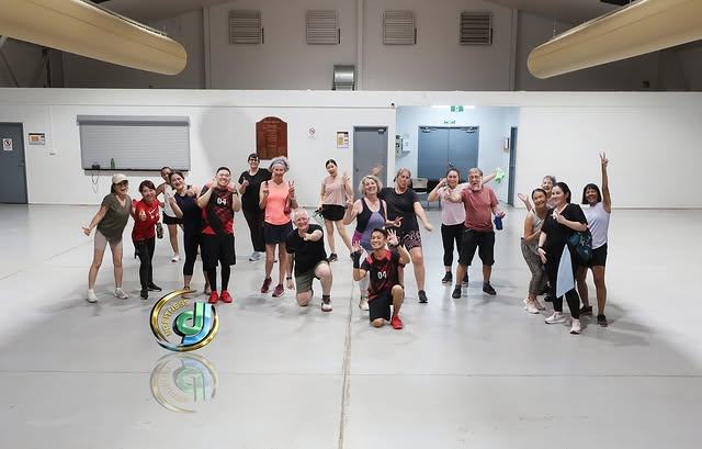 A post-class group photo in the sports hall, everyone still in workout gear.