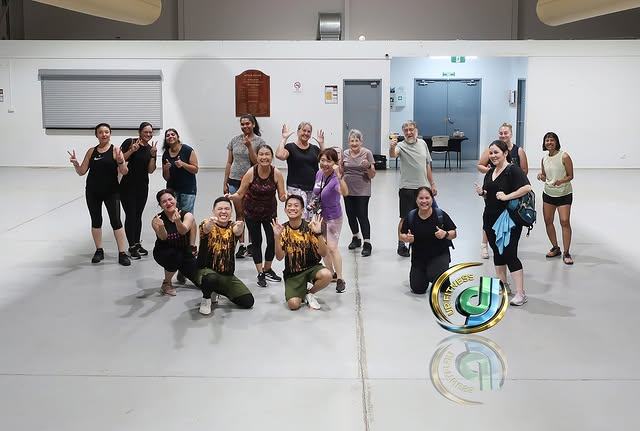 Participants grouped together smiling after finishing a class in the hall.