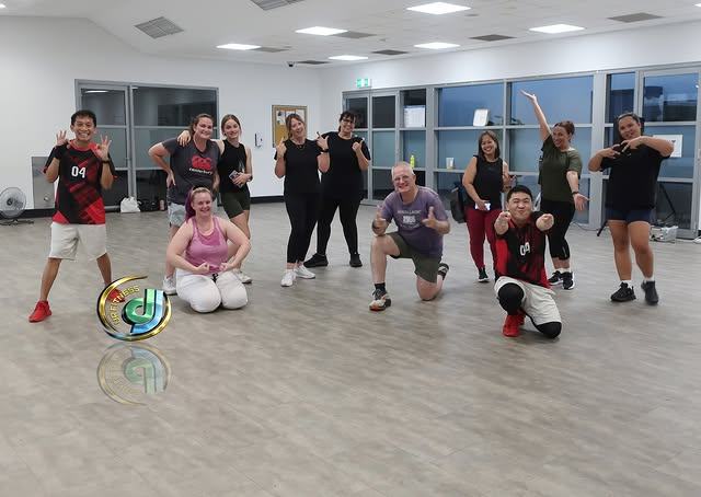 Class members smiling for a photo in the studio room after class.
