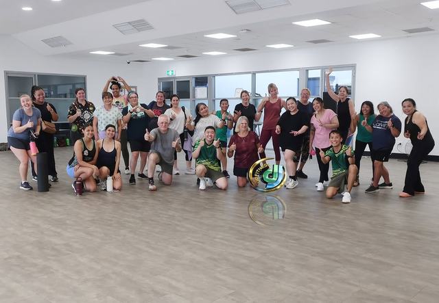 A group photo in the bright studio room with its wall of windows behind.