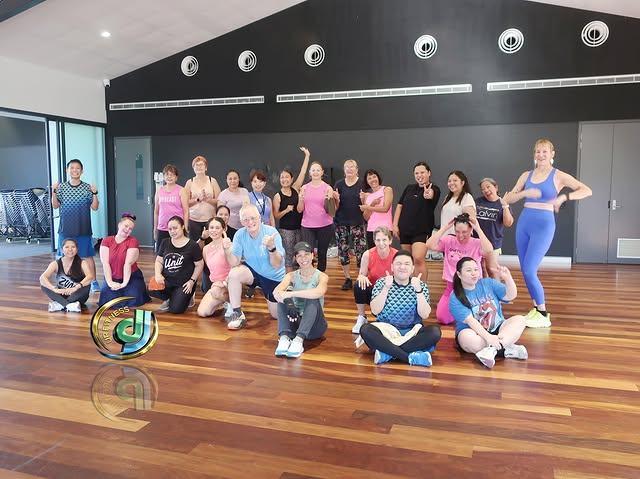 A group photo in the timber-floored hall after a class.